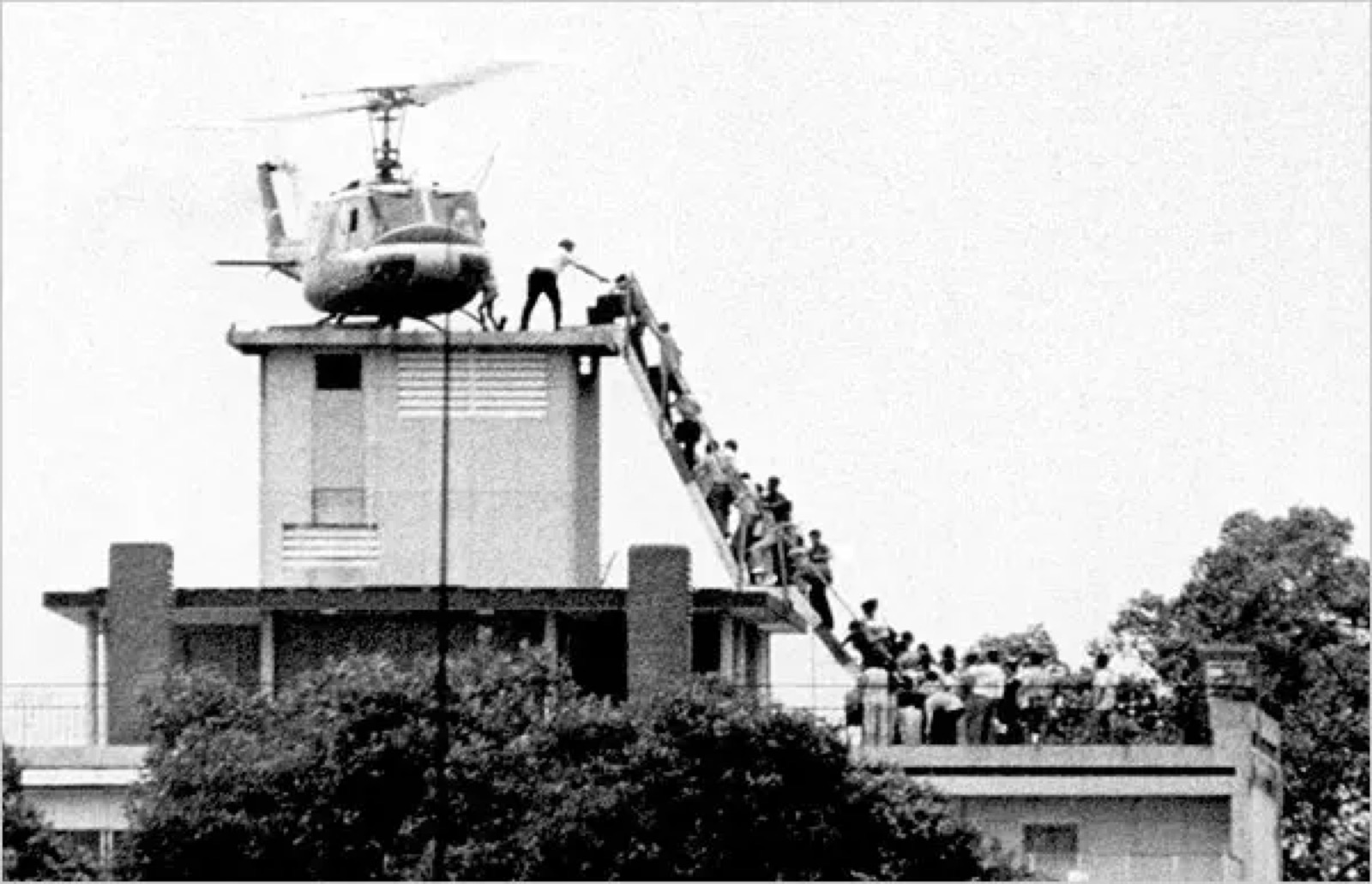 Evacuees climb a ladder to an Air America helicopter on a Saigon rooftop on 29 April 1975.
